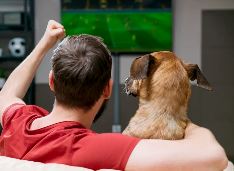 Мужчина смотрит телевизор с собакой